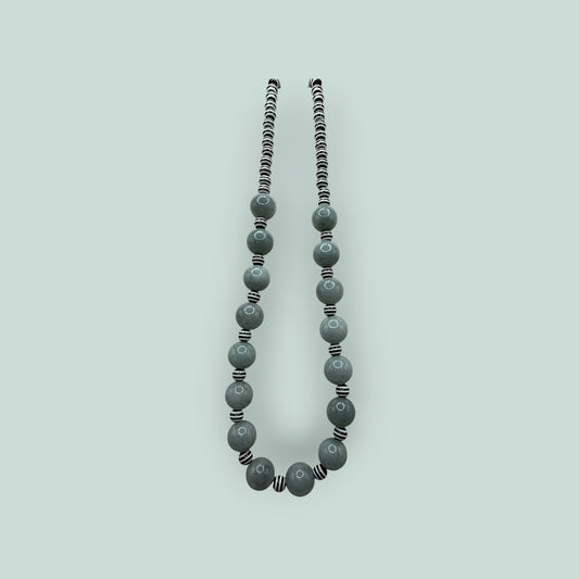 The Salty Bead Co handcrafted statement necklace featuring sage-green stone beads and black-and-white striped accents.