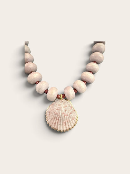 The Salty Bead Co coastal necklace with dusty-pink matte beads and a natural seashell pendant with gold-tone edging.