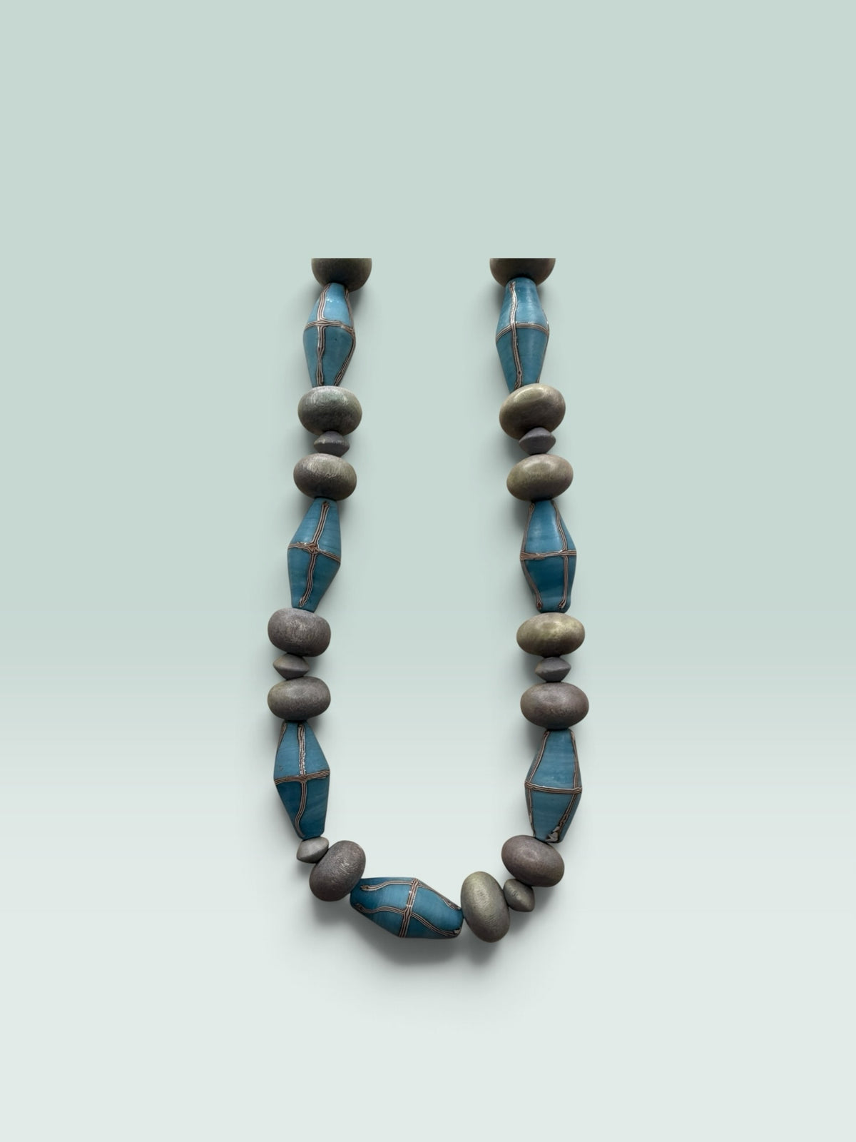The Salty Bead Co artisan statement necklace featuring slate-grey matte beads and teal diamond-shaped wire-accent beads.