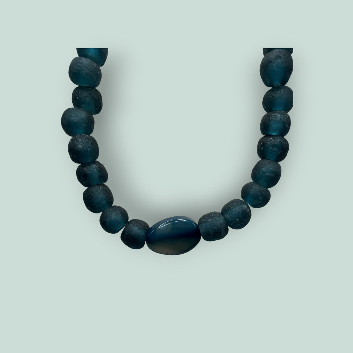 The Salty Bead Co handcrafted necklace featuring matte teal-blue beads and a polished oval centerpiece stone.