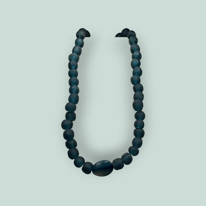 The Salty Bead Co handcrafted necklace featuring matte teal-blue beads and a polished oval stone centerpiece.