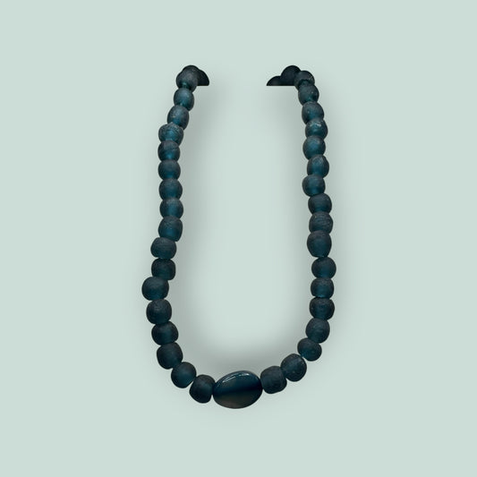 The Salty Bead Co handcrafted necklace featuring matte teal-blue beads and a polished oval stone centerpiece.