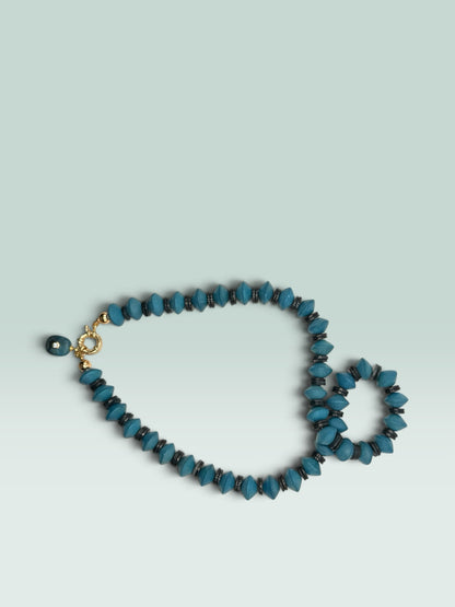 The Salty Bead Co handcrafted statement necklace with turquoise blue faceted beads, metallic spacers, and gold clasp.