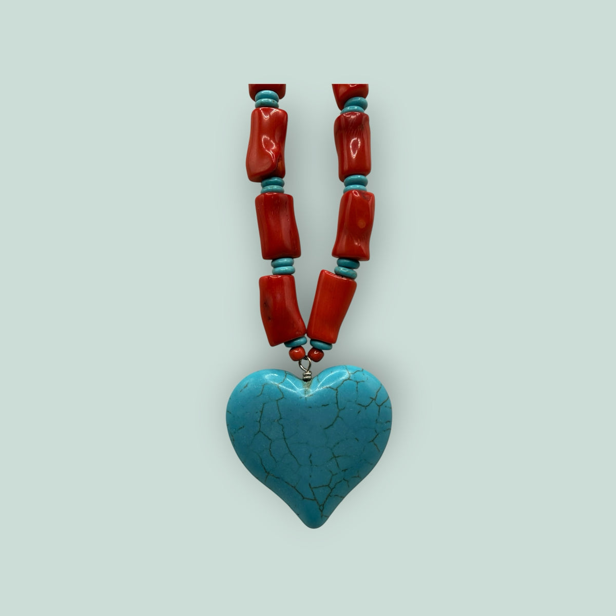 The Salty Bead Co artisan heart pendant necklace featuring a turquoise heart charm with red coral-style beaded strand.