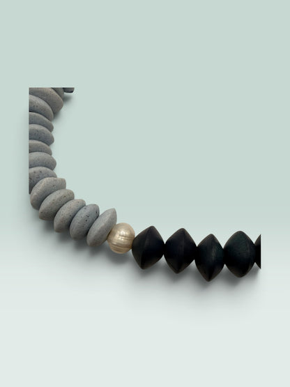 The Salty Bead Co two-tone statement necklace with slate-grey textured beads, matte black beads, and a central pearl.