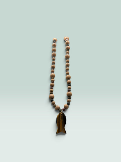 The Salty Bead Co handcrafted necklace with light wooden beads, dark stone accents, and a tiger's eye fish pendant.