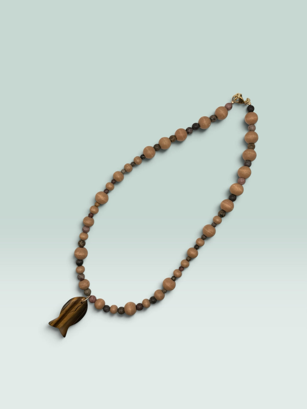 The Salty Bead Co handcrafted necklace with light wooden beads, dark stone accents, and a tiger's eye fish pendant.