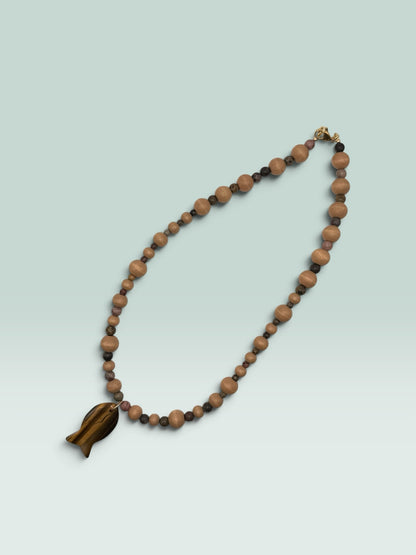 The Salty Bead Co handcrafted necklace with light wooden beads, dark stone accents, and a tiger's eye fish pendant.